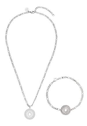 Silver chain necklace and matching bracelet each with a round pendant featuring a diamond-shaped cutout and decorative edges.