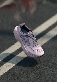 Light purple running shoe with mesh upper, padded collar, and textured sole, featuring prominent logo on the side and ventilation holes.