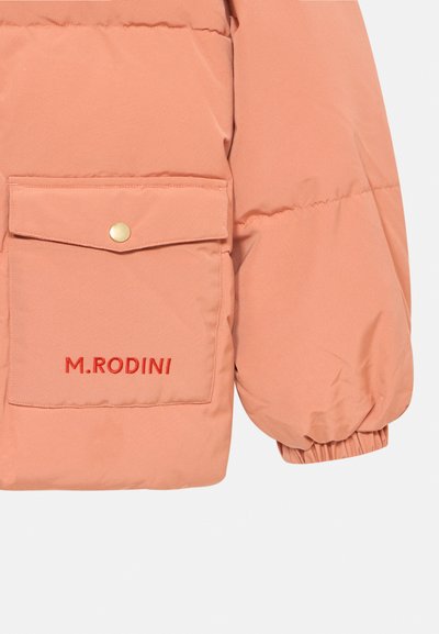 Nadmjerni jakna od mekanog breskvastog materijala s džepom na prsima i zlatnim dugmetom na preklop. "M. RODINI" je izvezeno crvenom bojom. Elastični rukavi osiguravaju usklađen izgled.