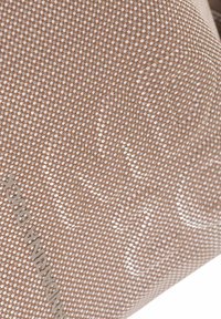 Tela marrón tejida con una superficie texturizada, que presenta patrones sutiles y un detalle de logotipo metálico en el costado.