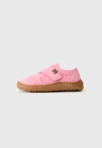 Des chaussons en feutre rose avec une semelle en caoutchouc marron, dotés d'une bande auto-agrippante. La forme arrondie et le design épuré améliorent le confort.