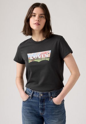 Juodas medvilninis marškinėliai su spalvingu Levi's logotipu priekyje. Su deriniais mėlynomis džinsinėmis kelnėmis, kurios pabrėžia klasikinį pjūvį ir dizainą.