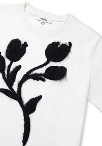 Witte t-shirt met een vlezige zwarte bloemenprint met drie tulp-achtige bloemen en bladeren op de voorkant, merklabel zichtbaar in de kraag.