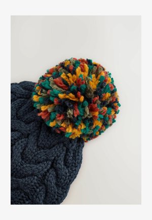 Gorro de punto en color navy con un gran pompón multicolor que incluye rojo, verde, amarillo y azul. Patrón texturizado en el sombrero.