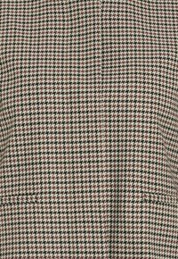 Auduma aušana ar suņu zobu rakstu melnā, baltā un bordo krāsā, ar strukturētu virsmu un vienu redzamu kabatu.