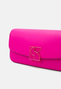 Clutch in pelle rosa con un logo geometrico dorato sulla patta, texture liscia, bordi arrotondati e design semplice.