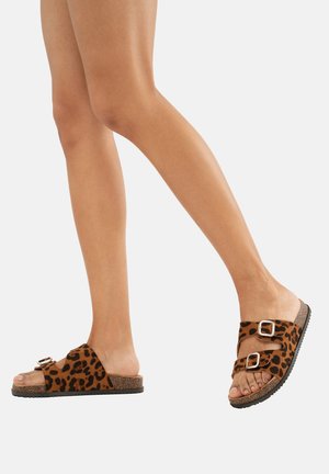 Leopardenmuster-Sandalen aus weichem Material mit zwei verstellbaren metallischen Schnallen, vorgestellt auf einer strukturierten Kork-ähnlichen Sohle.