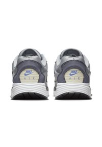 Szürke és fehér Nike sportcipők, texturált hátsó résszel, feltűnő kék logóval és "AIR" részletezéssel. Tartós gumitalp a tapadásért.