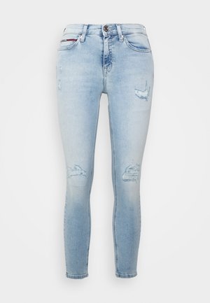 Light blue skinny jeans with distressed patches on thighs and knees, front button, and belt loops.