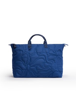 Borsa tote trapuntata blu con manici superiori e un sottile motivo astratto cucito su sfondo bianco.