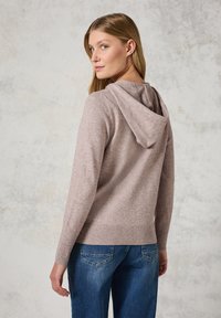 Pull à capuche en tissu doux de couleur marron clair, avec un ourlet et des poignets côtelés. Présente un design simple et une coupe décontractée.