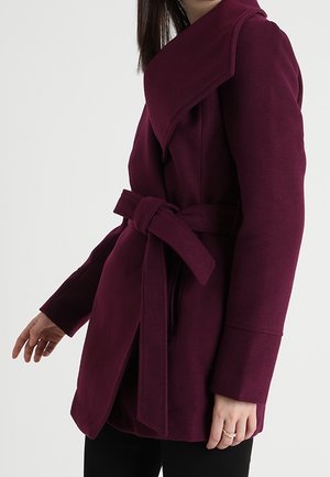 Bordowy płaszcz z kopertowym zapięciem, szerokimi klapami, paskiem w talii i fakturowaną tkaniną. Posiada długie rękawy i dopasowany krój.