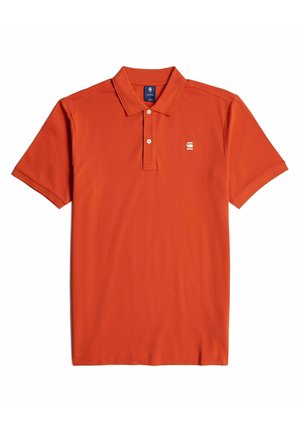 Polo naranja hecho de una tela suave, con cuello, mangas cortas y un pequeño logo en la parte izquierda del pecho.