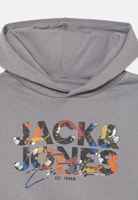 Šedá mikina s kapucňou, na ktorej je viacfarebný logotyp s nápisom "JACK & JONES essentials" a textúrovaný, škvrnitý dizajn s červenými, žltými a modrými akcentmi.