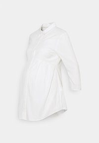 Vit gravidblus med knappstängning fram, krage och trekvartsärmar. Har rynkning vid midjan för komfort.