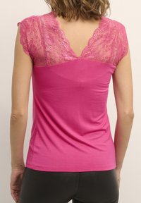 Růžový top s přiléhavým střihem a krajkovými detaily na ramenou a zádech. Hladká tkanina s klasickým designem výstřihu.