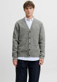 Grau gestrickte Wolle Cardigan mit V-Ausschnitt, Knopfschluss und gerippten Bündchen. Über einem weißen und blauen gestreiften Hemd getragen. Locker sitzendes Design.