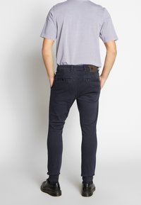 Tyrkysově modré slim fit džíny z bavlněné směsi s jemnou strukturou. Mají dvě zadní kapsy a logo našité na pásku v pase.