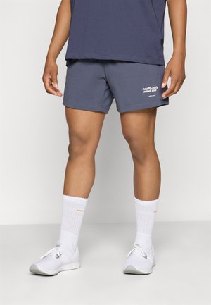 Navy shorts with a white logo, cotton blend material, above-knee length, paired with white athletic socks and shoes. Plain design.