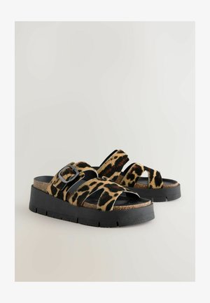 Sandales en imprimé léopard avec des sangles noires et une fermeture à boucle. Elles disposent d'une semelle en liège et d'une épaisse semelle noire.