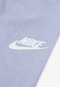 Απαλό μπλε υφασμάτινο ύφασμα με λεία υφή, που διαθέτει το εξέχον λευκό λογότυπο της Nike στην κάτω γωνία.