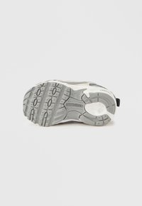 Γκρι λαστιχένια εξωτερική σόλα αθλητικού παπουτσιού με διάφορα σχέδια πέλματος και λευκή φτέρνα. Διαθέτει λογότυπο της μάρκας και υφασμένες περιοχές για καλύτερη πρόσφυση.