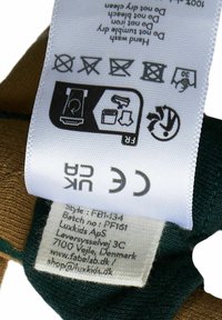 Label van een bruine en groene stof, met wasinstructies, veiligheidssymbolen en contactgegevens gedrukt op wit materiaal.