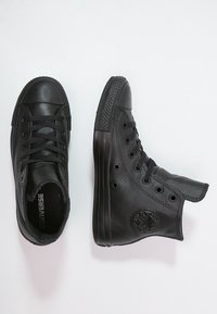 Černé kožené vysoké tenisky Converse mají zaoblenou špičku, šest otvorů na šněrování, strukturovanou gumovou podrážku a embosované logo na boku.