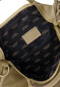 Beżowa skórzana torebka w środku, wykończona czarną tkaniną. Podszewka zdobiona złotymi wzorami logo "Venezia" oraz kieszenią na zamek.