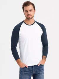 Raglan langærmet skjorte i hvid med marineblå ærmer, bomuldsblanding, rund hals, tætsiddende design, diskrete ærmedetaljer, båret med jeans.