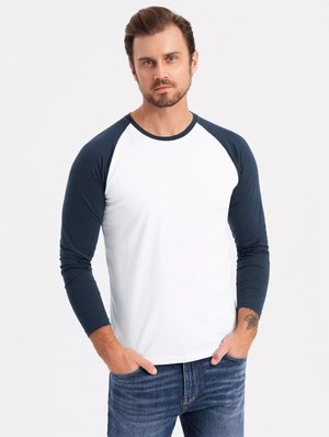 Raglan langemouw shirt in het wit met marineblauwe mouwen, katoenmix, ronde hals, aansluitend ontwerp, subtiele mouwaccenten, gedragen met jeans.