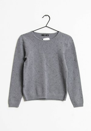 Maglione grigio lavorato a maglia con scollo tondo, maniche lunghe, motivo strutturato e orlo a coste. Realizzato in materiale morbido e caldo. Appeso a un gancio nero.