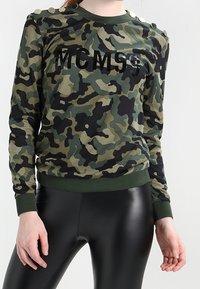 Felpa con motivo camouflage in verde scuro e beige con scritte nere. Presenta bottoni sulle spalle e polsini e bordo a coste.