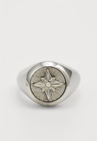 Sølvring med kompassdesign som har en diamant i sentrum, gravert med retninger (N, Ø, S, V), og med teksturert solstrålebakgrunn.