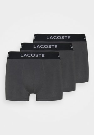 Three pairs of gray cotton-boxer shorts with a black waistband featuring the "Lacoste" logo in white. Smooth texture, fitted design.