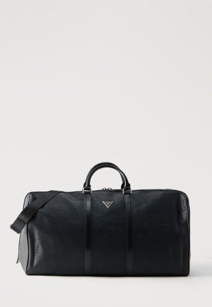 Borsa da viaggio in pelle nera lavorata con doppi manici, tracolla removibile e piccolo logo metallico triangolare sul davanti.