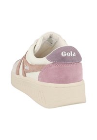 Baskets blanches avec des accents en daim rose pâle et beige. Elles présentent une semelle texturée, un logo sur le talon et un design de coloris distinctif.