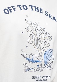 Κείμενο «Off to the Sea» πάνω από εικονογραφίες με κοράλλια, κοχύλια και αστερίες με τη φράση «Good Vibes Barbados» από κάτω σε λευκό ύφασμα.