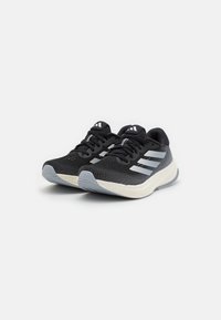 Baskets de sport noires avec une tige en mesh respirant, des accents gris et une semelle légère. Présente trois rayures blanches sur le côté extérieur.