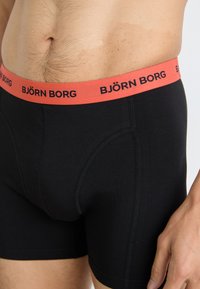 Fekete boxer alsónadrág korall színű, elasztikus derékszíjjal, amelyen fekete "BJÖRN BORG" logó található. Az anyag lágy és testhez simuló hatású.