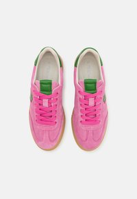 Pink suede sneakers with green accents, featuring round laces, cushioned interior, and a gum rubber sole. Classic athletic design.