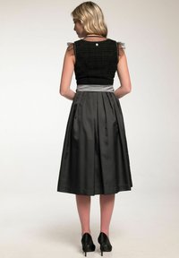 Schwarzes ärmelloses Top mit strukturiertem Stoff und transparenten, punktakzentuierten Ärmeln, kombiniert mit einem knielangen A-Linien-grauen Rock und schwarzen High Heels.
