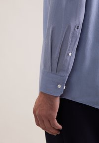 Blauw gemêleerd overhemd met een gestructureerde stof, manchetten met knopen en een slim fit ontwerp, met zichtbare stiksels en details op de mouw.