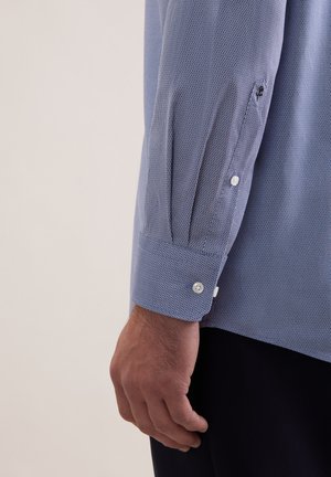Blå mønstret skjorte med tekstureret stof, knapmanchetter og et slankt snit, med synlige sømme og detaljer på ærmet.
