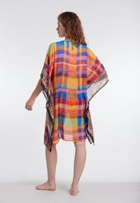 Mitmevärviline kimono-stiilis katteese, millel on ruuduline muster sinise, oranži ja kollase tooni, läbipaistev kangas ning kontrastne must äär.