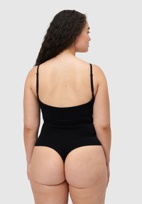 Černý body s tenkými ramínky, vysokým rozparkem na nohách, hladkou texturou a přiléhavým střihem. Pohled zezadu ukazuje plné pokrytí.