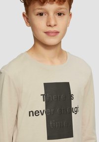 Lichtbeige langemouw shirt met een zwarte rechthoekige grafiek met de tekst "Er is nooit genoeg tijd." Soepele katoenstructuur.