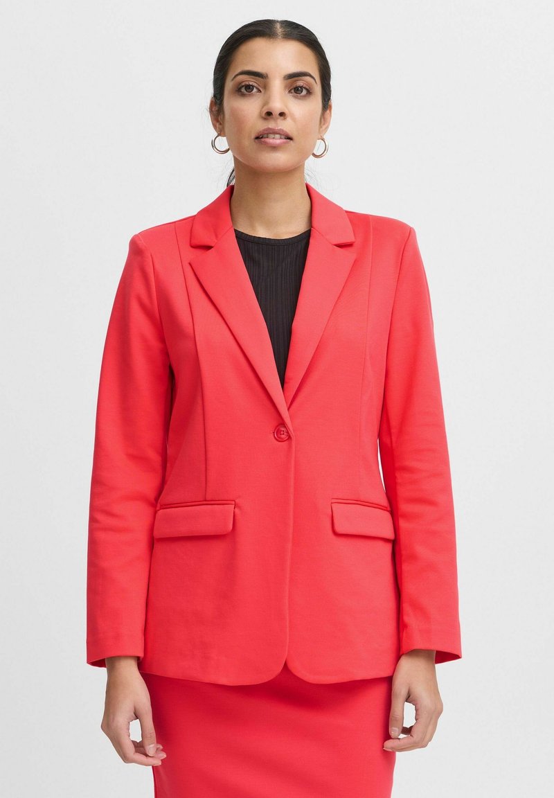 Koraalblazer met een enkele knoopsluiting, twee voorzakken en ingeknipte revers. De stof oogt soepel, ontworpen voor een getailleerde silhouet.