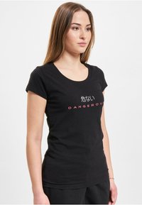 Black crew neck t-shirt made of cotton. Features white Japanese text and red “DANGEROUS” print on the front. Short sleeves, fitted design.