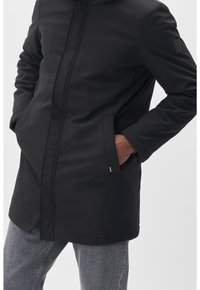 Manteau noir à manches longues en tissu lisse avec une fermeture éclair complète, des poches latérales et un ourlet arrondi. Présente un petit logo sur la manche.